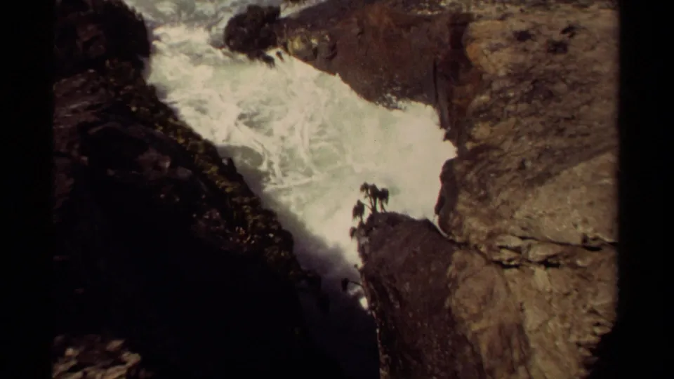 1980 Mendocino, California 8mm still of bright rushing water against shadowed rock and tan cliff surfaces.