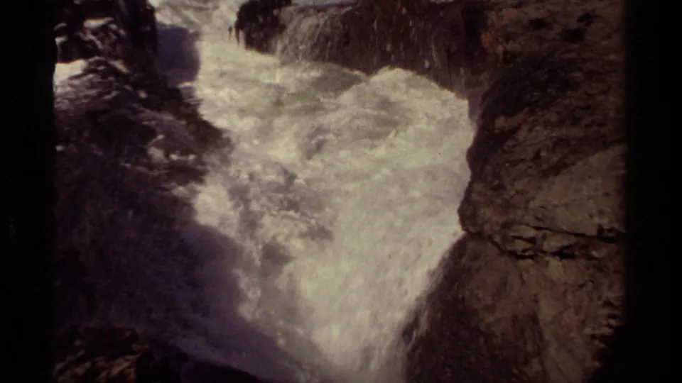 A grainy 1980 8mm frame shows Mendocino white water receding and swirling inside a narrow rocky inlet.