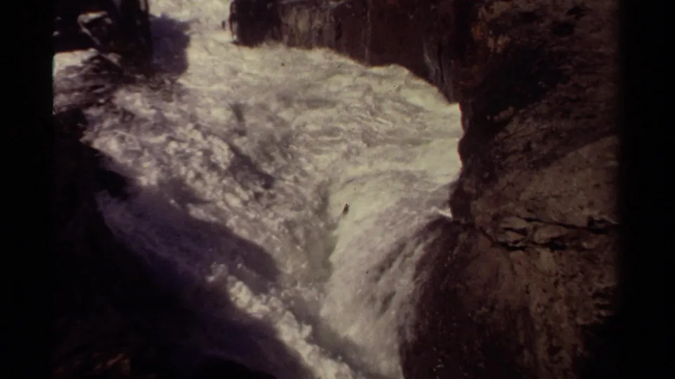 1980 Mendocino 8mm frame showing turbulent white water squeezed between dark coastal rocks.