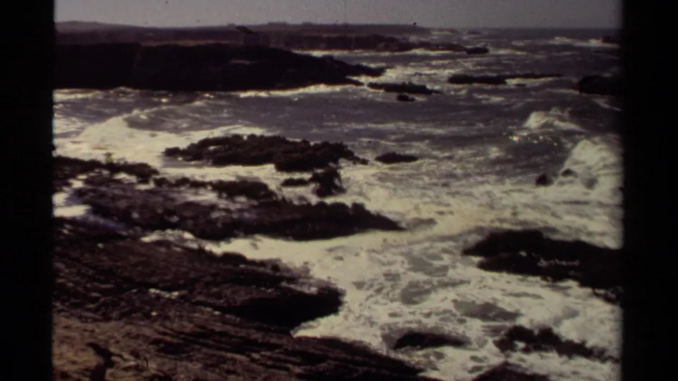 Mendocino coast surf churns around black rock formations in faded 1980 8mm footage.