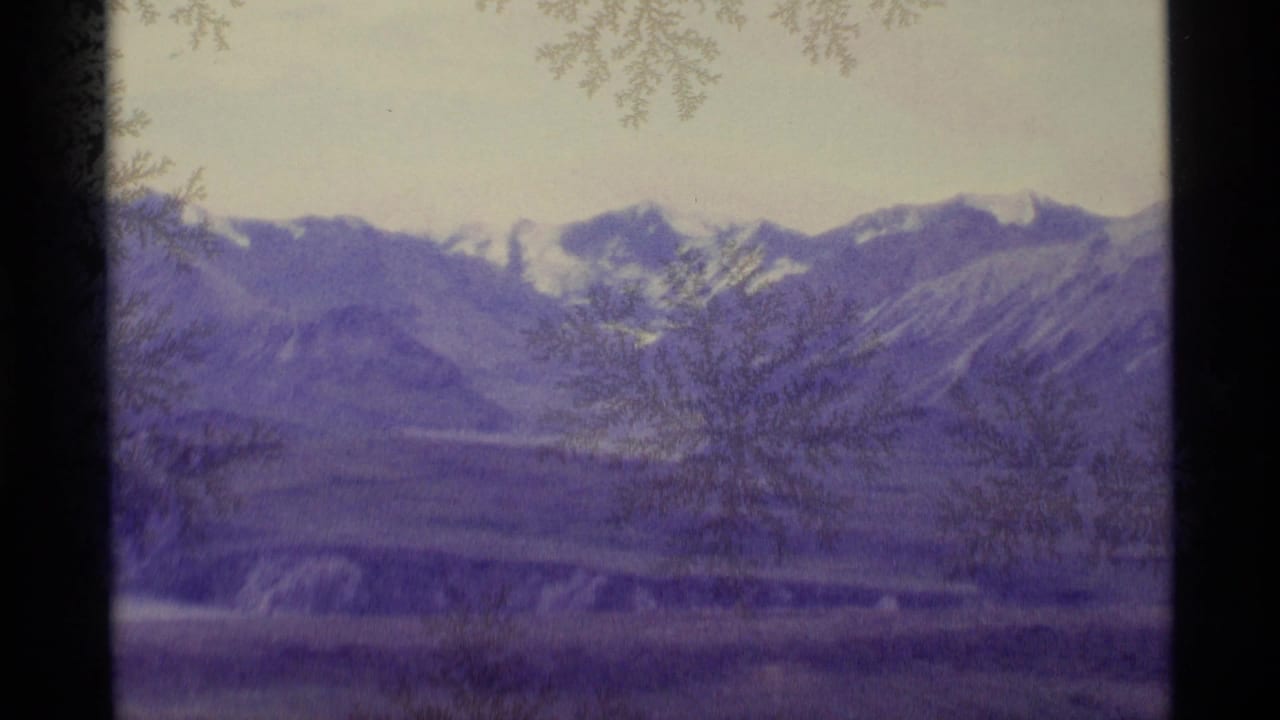 Purple-tinted mountain range seen through a frosted window with a dark divider at left.