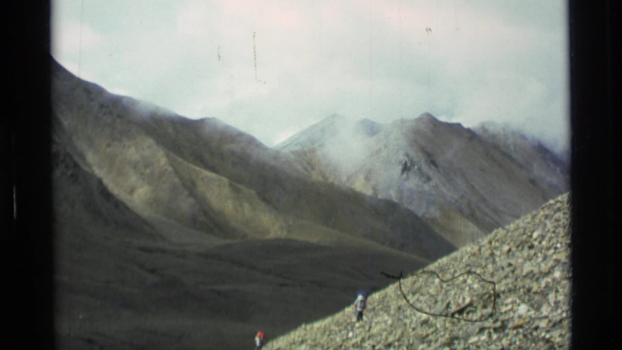 Foggy mountain valley with hikers on a rocky slope in the foreground.