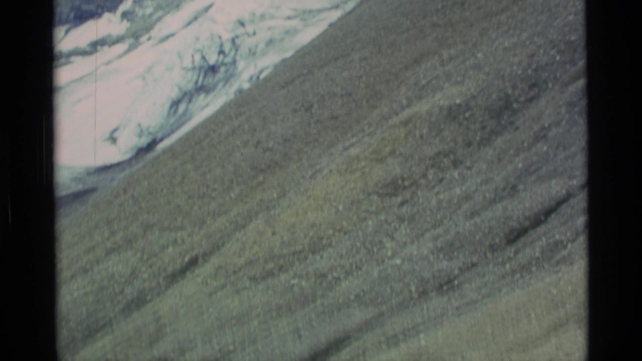 1977 Alaska 8mm view across a barren rocky slope toward glacier ice and snow above.