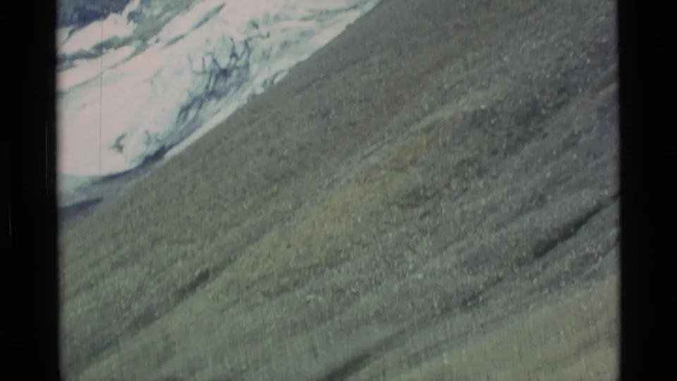 1977 Alaska 8mm view across a barren rocky slope toward glacier ice and snow above.