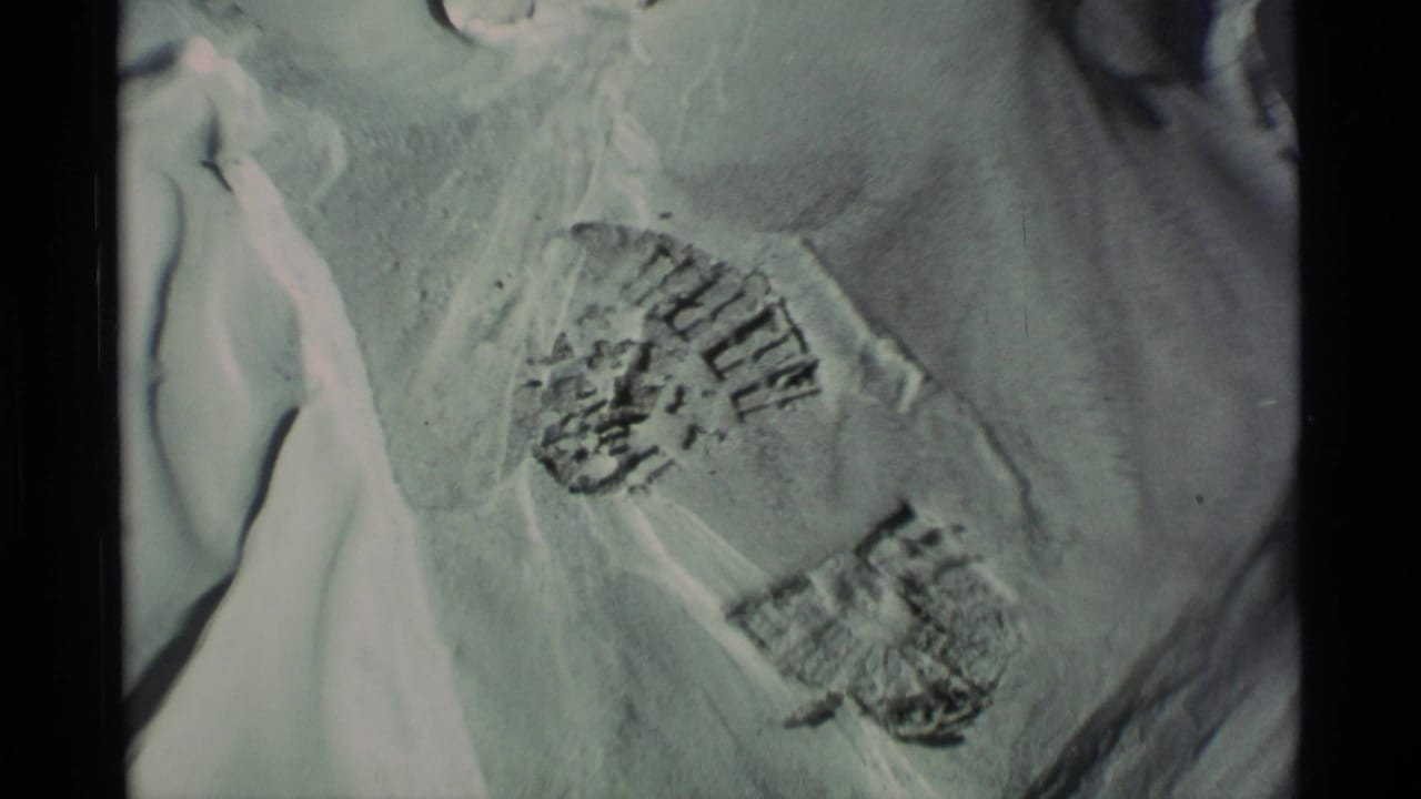 1977 Alaska 8mm frame showing close boot prints in snow with soft exposure and dark film borders.