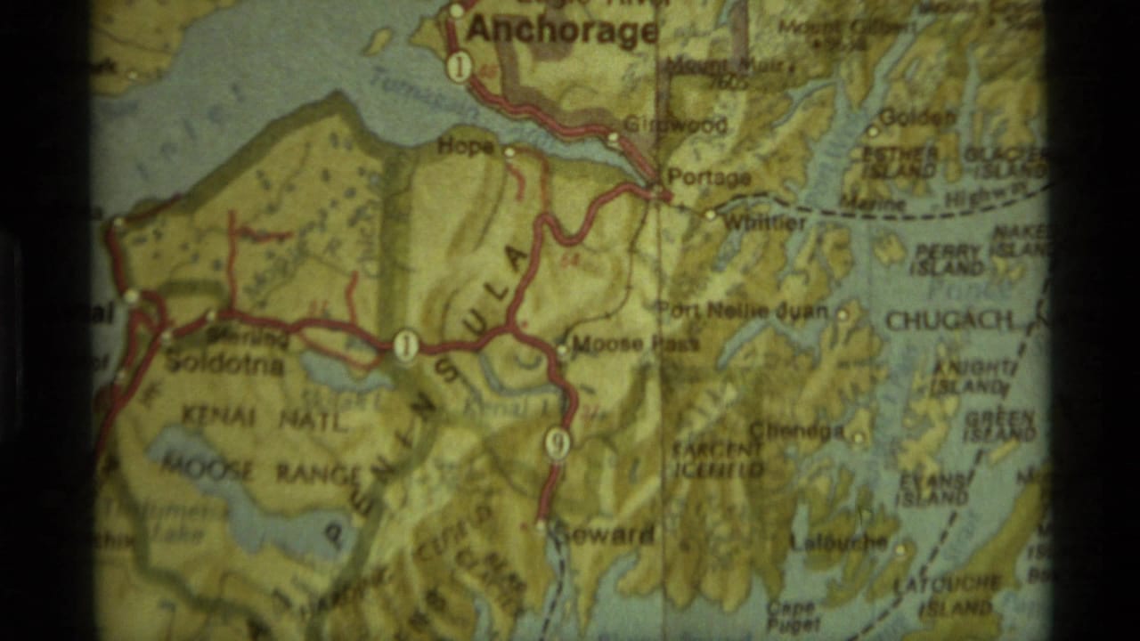Close-up of a printed Alaska map showing Anchorage, the Kenai Peninsula, and red highway routes.