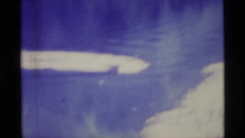 1977 Alaska 8mm frame with a purple-blue sky and pale cloud forms, softened by exposure and film color shift.