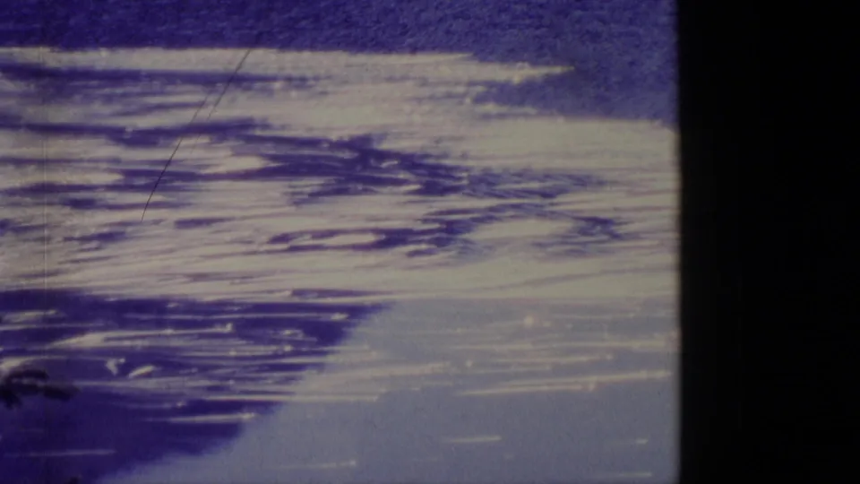 1977 Alaska 8mm frame with broad snow or ice streaks and darker bands across a frozen landscape below a blue sky.