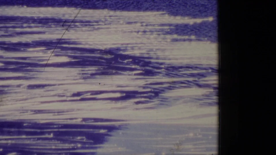 1977 Alaska 8mm frame showing snow or ice patterns across a remote landscape, with blue sky and visible scratches from the film scan.