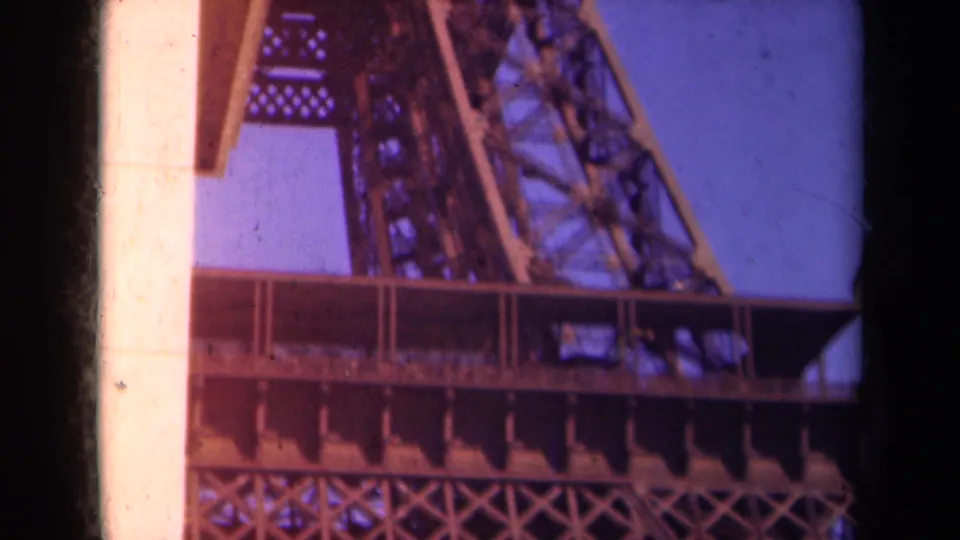 1939 Paris frame with the Eiffel Tower's platform, diagonal ironwork, and a pale vertical foreground edge under blue sky.