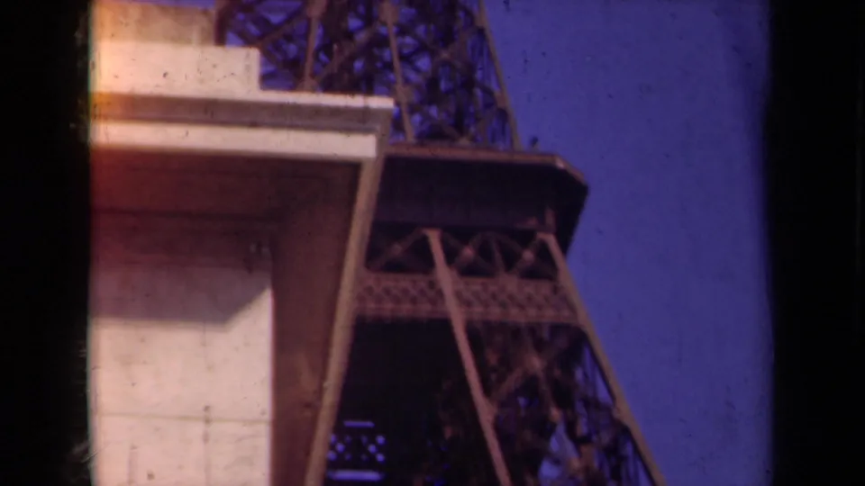 1939 Paris frame showing Eiffel Tower latticework partly obscured by the underside of a pale nearby structure.