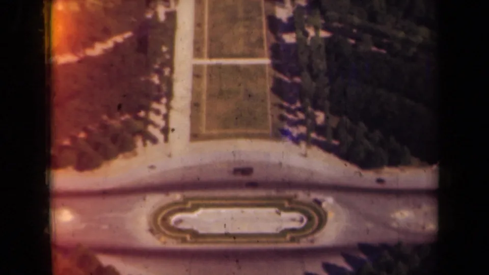 1939 Paris frame looking down toward formal grounds with trees, paths, a facade, and a central fountain-like feature.