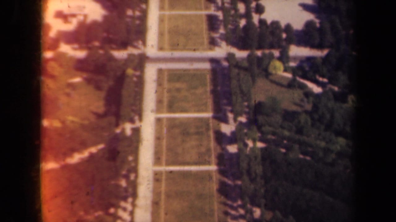 1939 Paris 8mm frame with symmetrical garden lawns, pale paths, and dense trees seen from an elevated viewpoint.