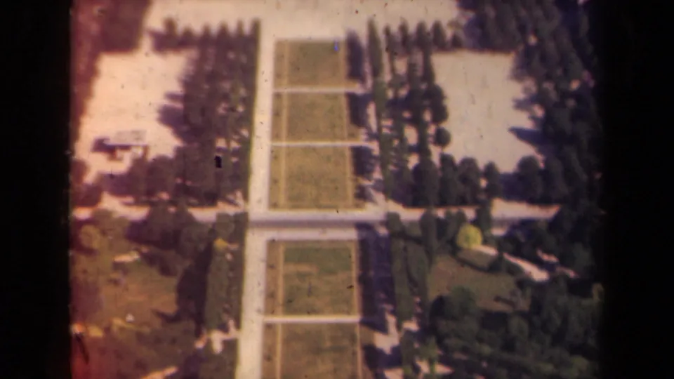 1939 Paris garden view showing geometric lawns, pale walkways, and orderly trees in soft 8mm color.