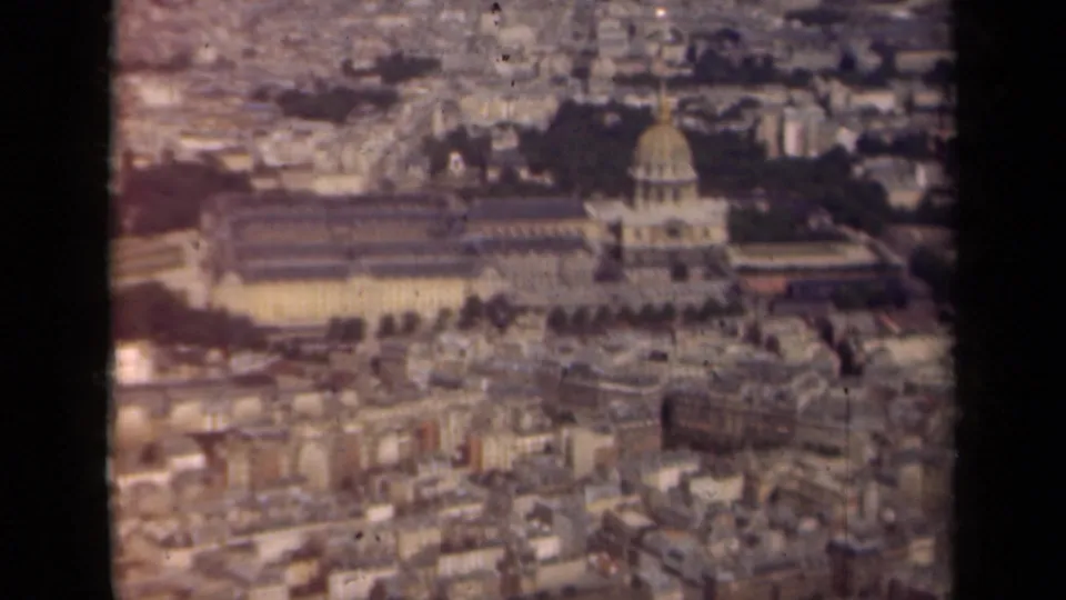 1939 Paris home-movie frame looking across a large domed structure, nearby rooftops, and a hazy urban landscape.