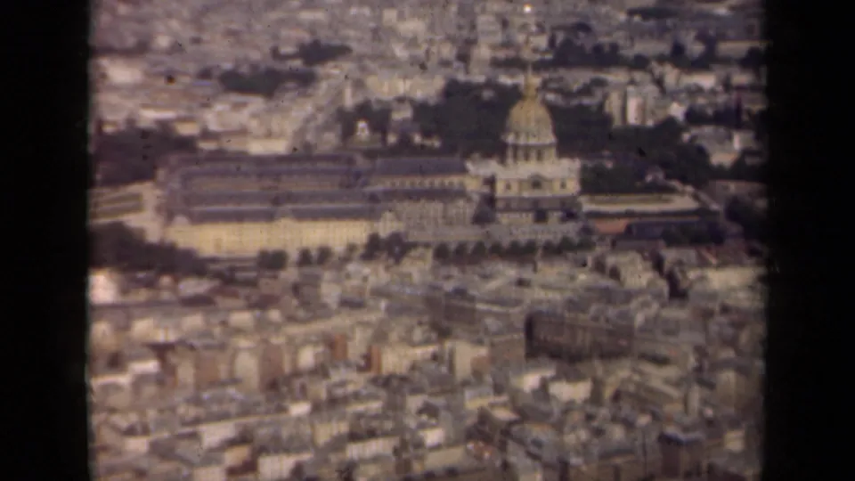 1939 Paris aerial home-movie frame showing the Les Invalides dome amid rooftops, trees, and a hazy cityscape.