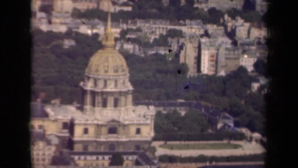 1939 Paris aerial home-movie frame with Les Invalides dome, surrounding greenery, and dense city buildings beyond.