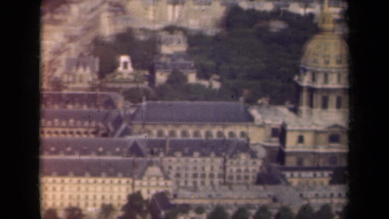 1939 Paris frame showing Hôtel des Invalides from above, with the dome at right, courtyards, rooflines, and distant city blocks.