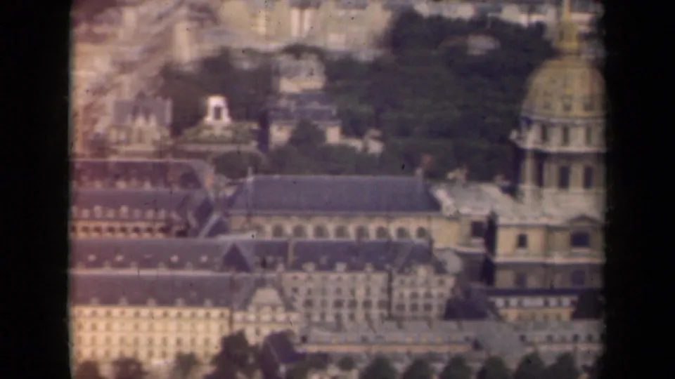 1939 Paris frame showing Hôtel des Invalides from above, with the dome at right, courtyards, rooflines, and distant city blocks.