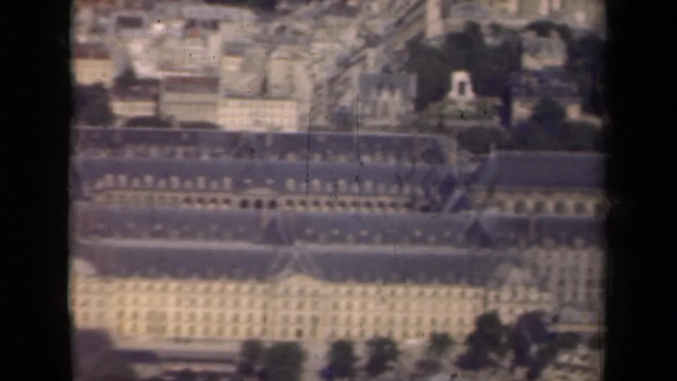 1939 Paris home-movie still looking over the long roofs of Hôtel des Invalides toward surrounding buildings and tree-lined grounds.