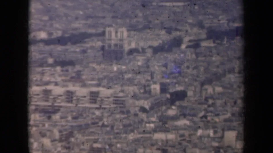 1939 Paris aerial view showing dense rooftops, cathedral-like towers, and soft 8mm film texture within a contact-sheet frame.