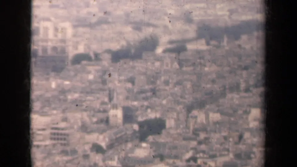 1939 Paris aerial frame with rooftops, church spire, cathedral-like towers, and visible 8mm exposure fading.