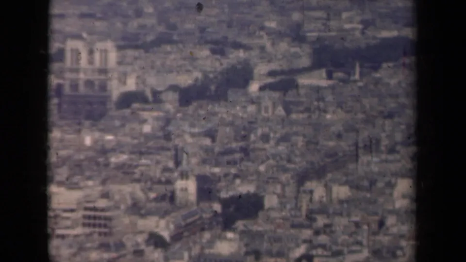 1939 8mm aerial view over central Paris, with Notre-Dame visible beyond dense rooftops and dark film borders.