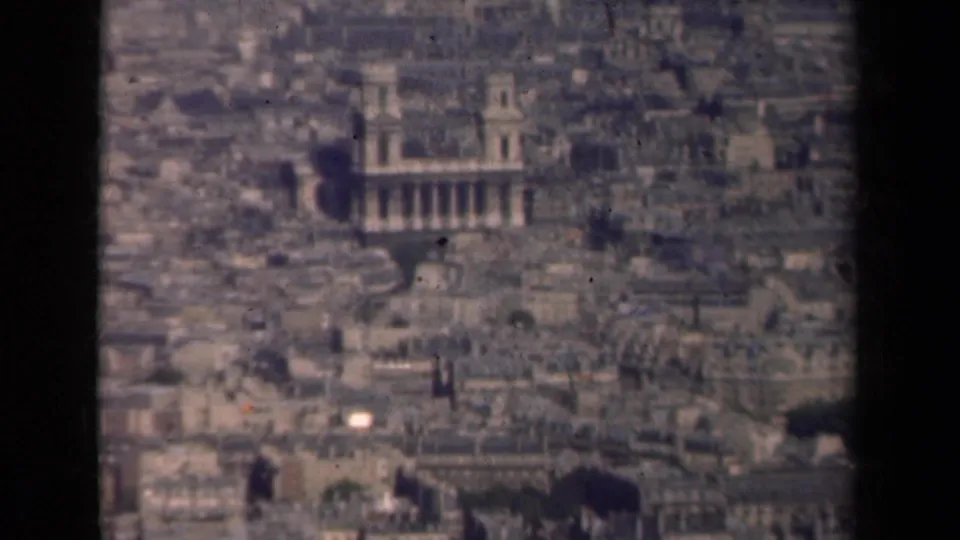 1939 8mm aerial view across Paris, with rooftops and a large columned landmark building visible in the lower frame.