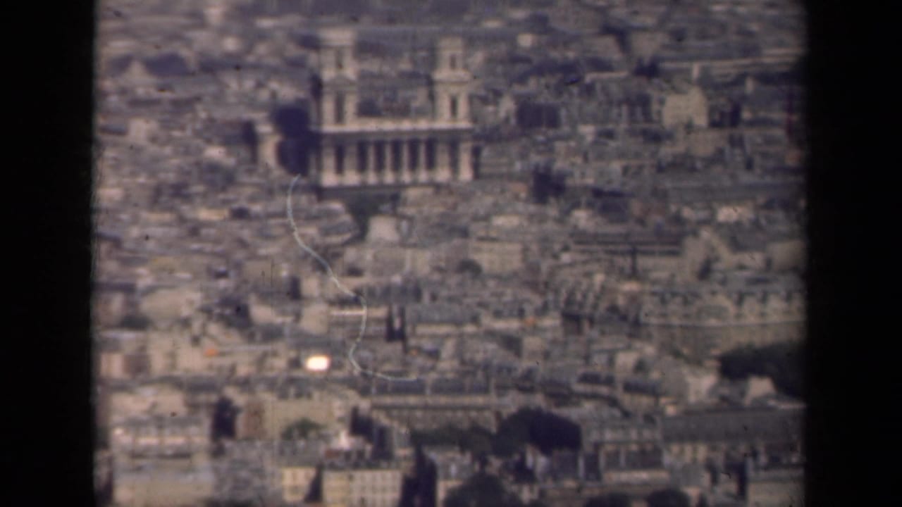 1939 Paris cityscape seen from above, with a large historic building rising among dense rooftops.