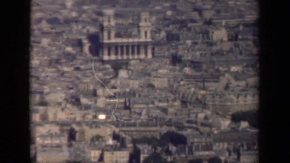 1939 Paris cityscape seen from above, with a large historic building rising among dense rooftops.