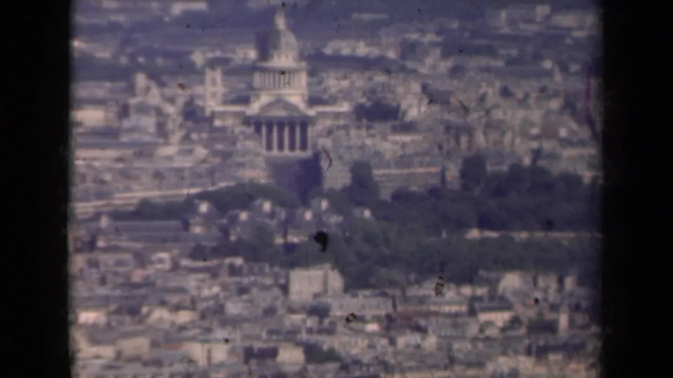 1939 Paris home-movie frame showing the Invalides dome from a high, hazy vantage point above dense rooftops.
