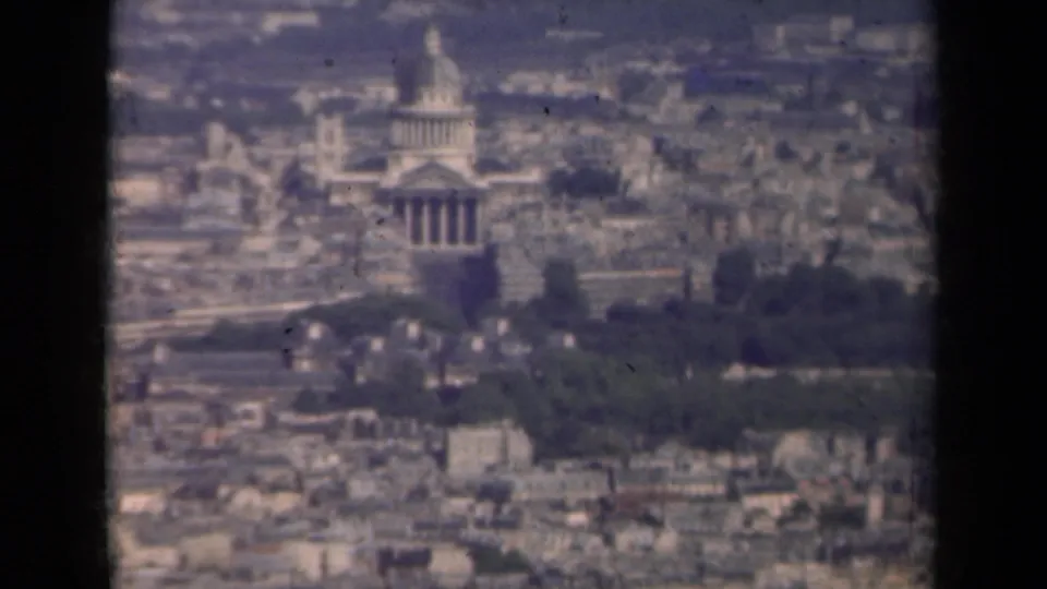 Elevated 1939 Paris view with the Invalides dome centered above rooftops and soft haze across the city.
