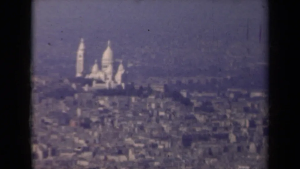 1939 8mm frame showing Sacre-Coeur on Montmartre through haze above Paris city blocks.