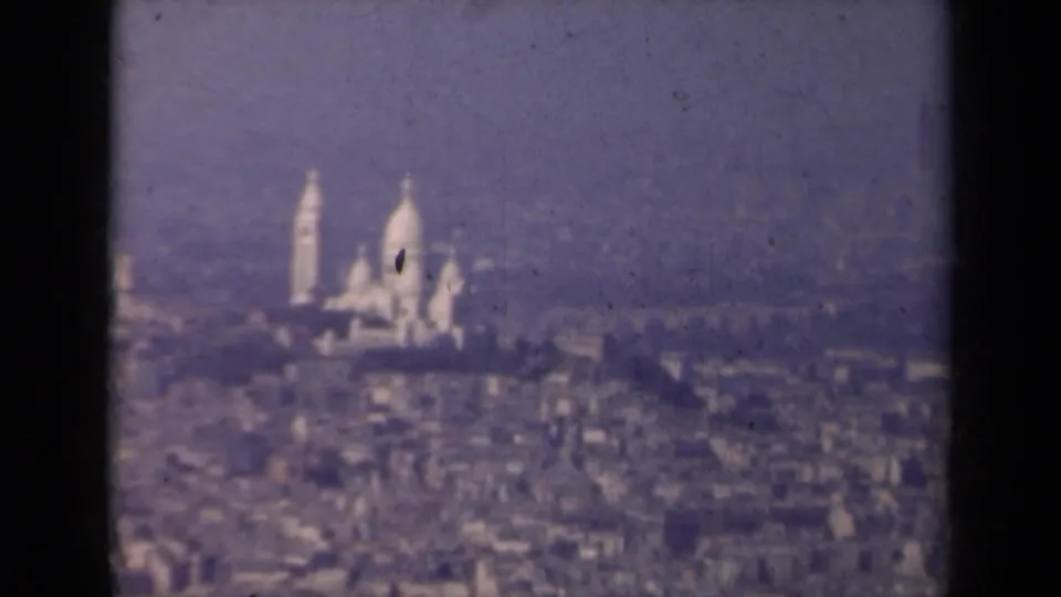 1939 Paris frame with Sacre-Coeur partially softened by haze and grain over the city.