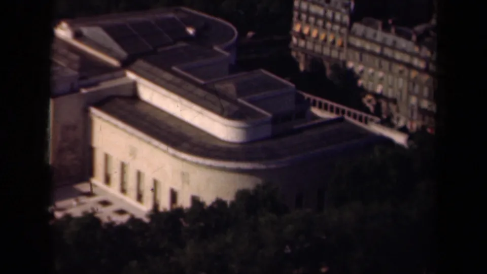 1939 Paris 8mm frame showing a modernist building exterior with rounded roof lines, trees, and nearby facades.