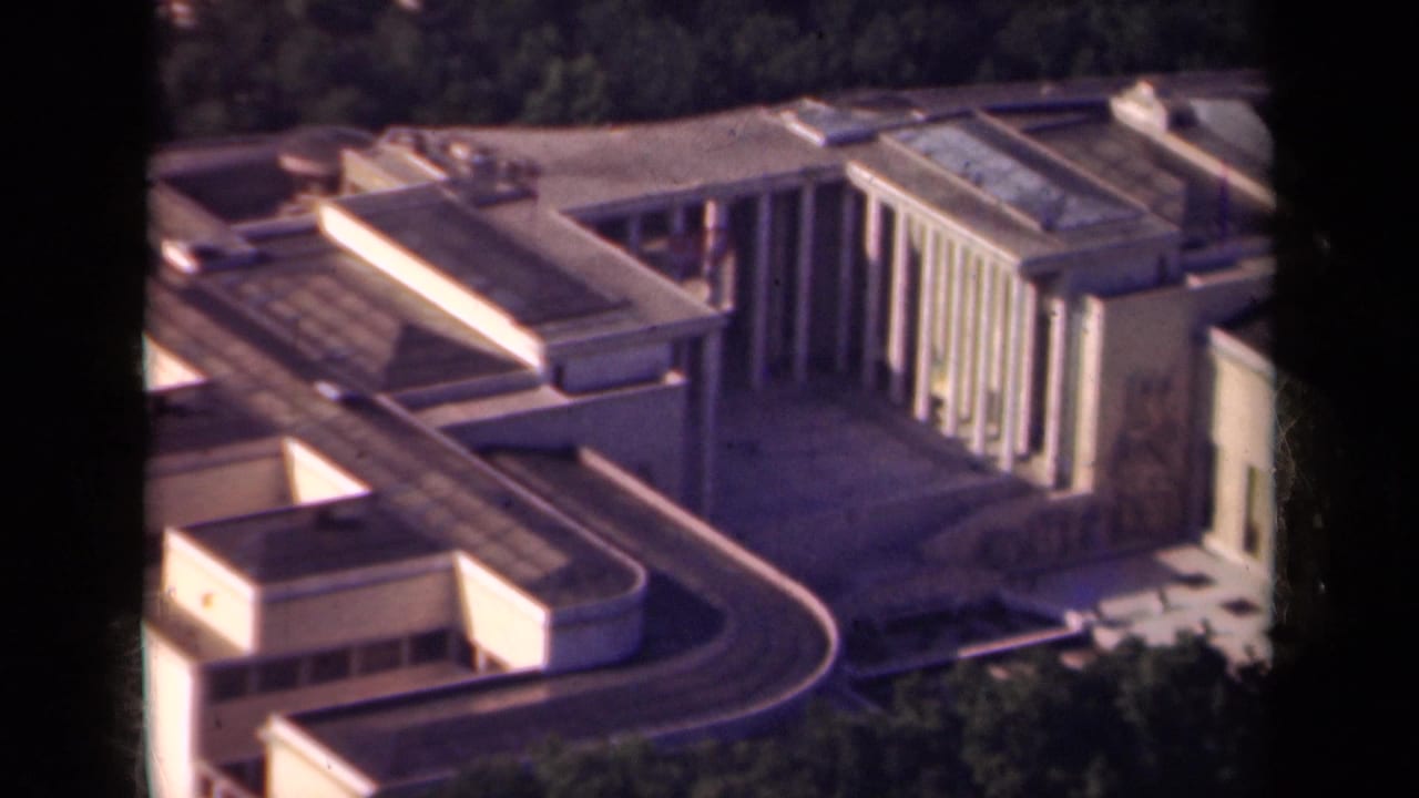 Aerial view of a modern building complex with flat roofs and a curved roadway.