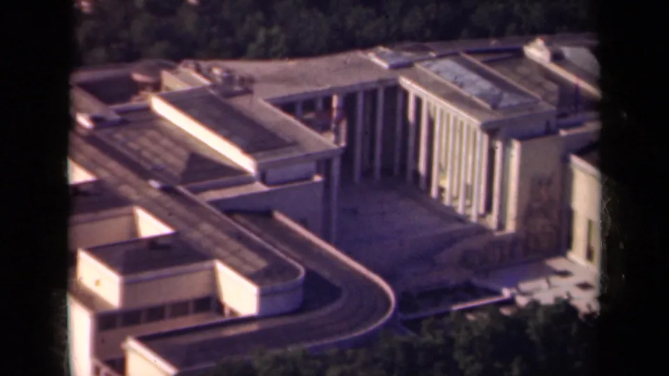 1939 Paris aerial frame showing a modern geometric building complex with flat roofs, columns, trees, and a curving roadway.