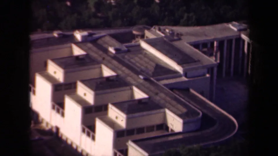 1939 Paris aerial frame showing flat-roofed blocks, a sweeping roadway, trees, and the edge of a modern building complex.