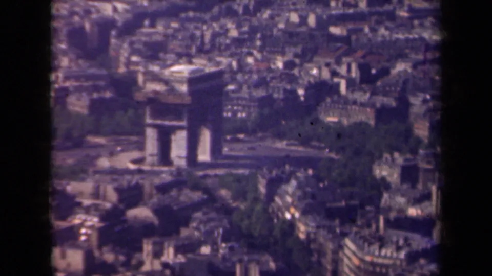 1939 Paris aerial frame showing the Arc de Triomphe surrounded by dense urban blocks, broad streets, and trees.