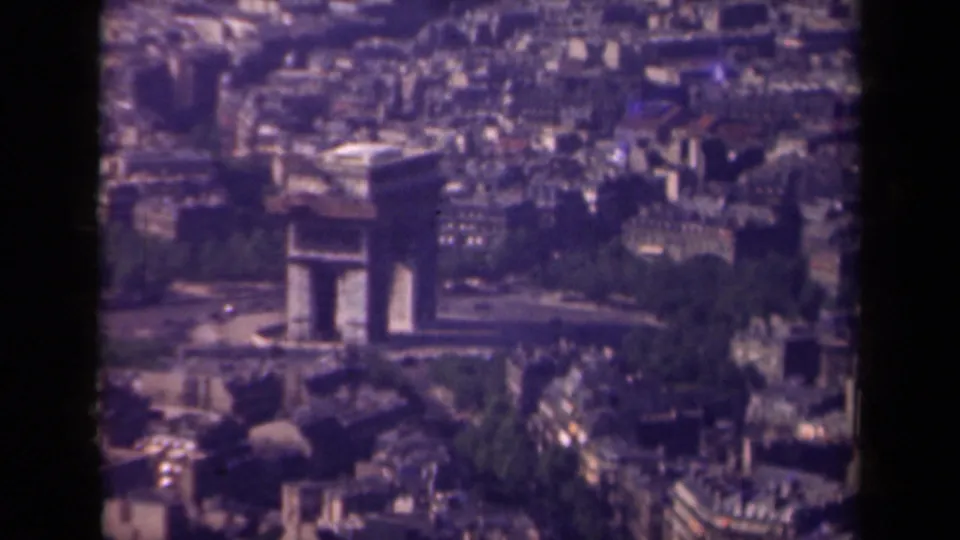 1939 Paris 8mm frame showing the Arc de Triomphe from above, with nearby avenues, rooftops, and trees softened by film grain.