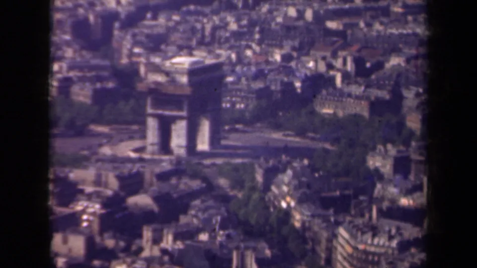 1939 8mm frame of the Arc de Triomphe in Paris, seen from above with greenery, rooftops, and broad streets visible around the monument.