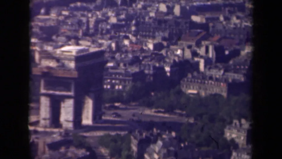 1939 Paris aerial view of the Arc de Triomphe, with cars moving around the roundabout and dense city blocks beyond.