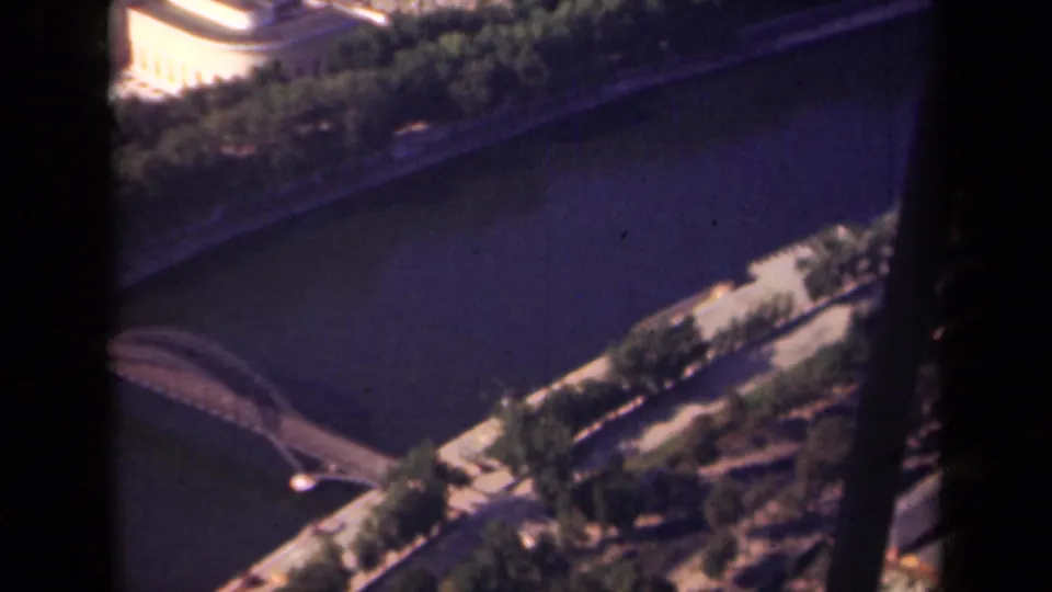 1939 Paris footage looking down on the Seine with a bridge, embankment trees, riverside roadway, and city buildings.