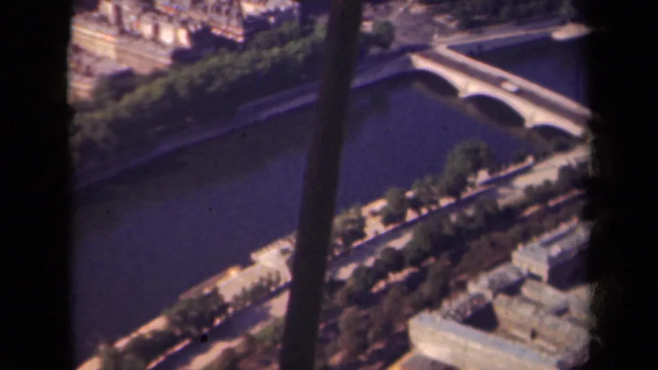 1939 Paris aerial frame showing a pale bridge across the Seine, tree-lined embankments, and surrounding city blocks.