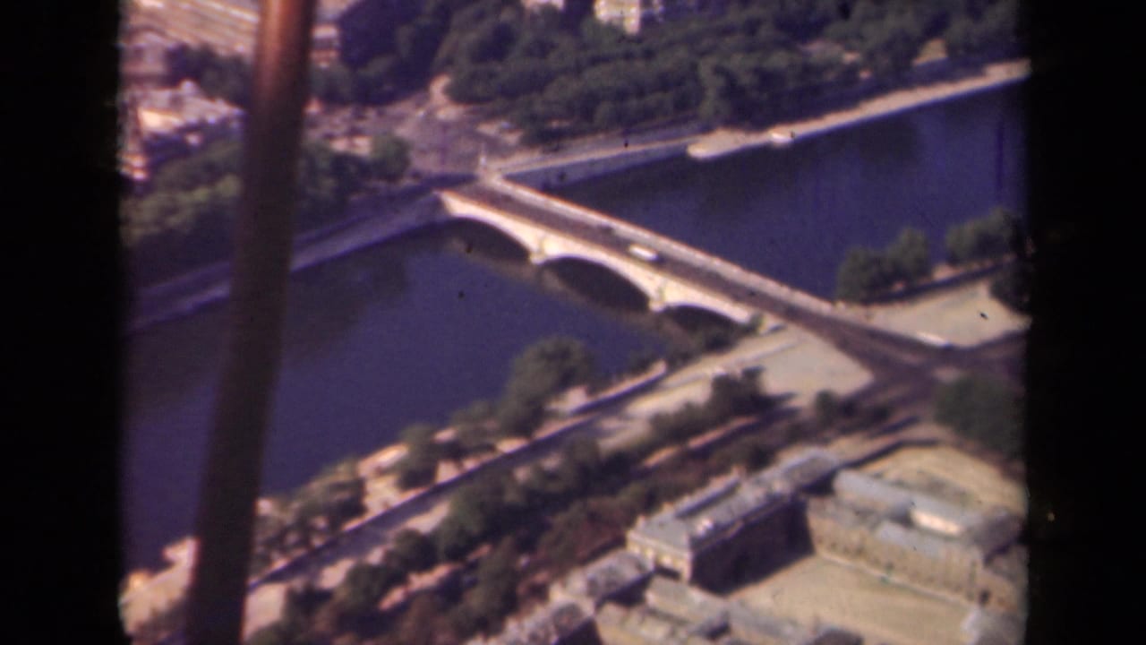 1939 Paris aerial view with a multi-arch bridge crossing the Seine, tree-lined banks, nearby buildings, and visible dark borders.