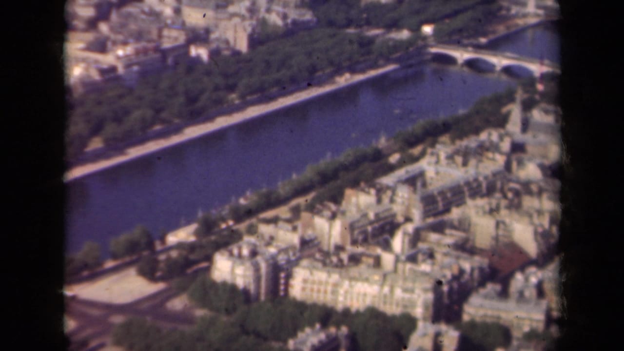 Aerial 1939 Paris view with the Seine running diagonally, a bridge at upper right, riverside trees, and clustered rooftops.