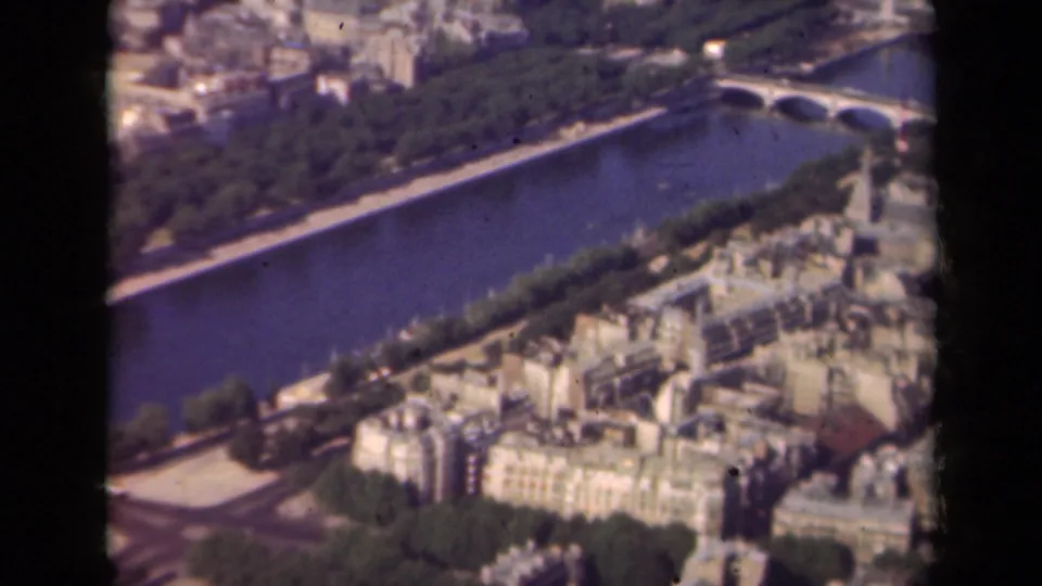 Aerial 1939 Paris view with the Seine running diagonally, a bridge at upper right, riverside trees, and clustered rooftops.