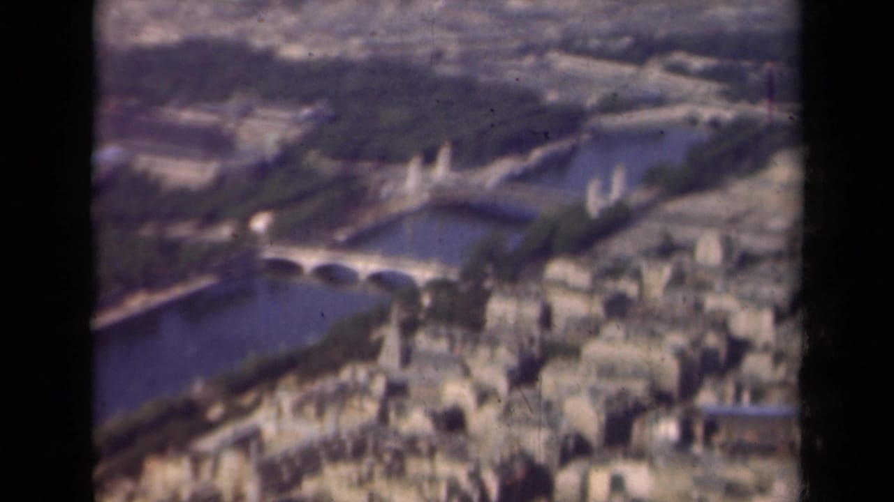 1939 aerial 8mm view over Paris showing the Seine, bridge spans, green park areas, and clustered city blocks.