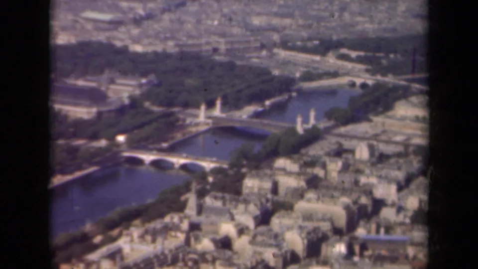 1939 Paris aerial frame showing the Seine, multiple bridges, parkland, and compact riverside architecture.