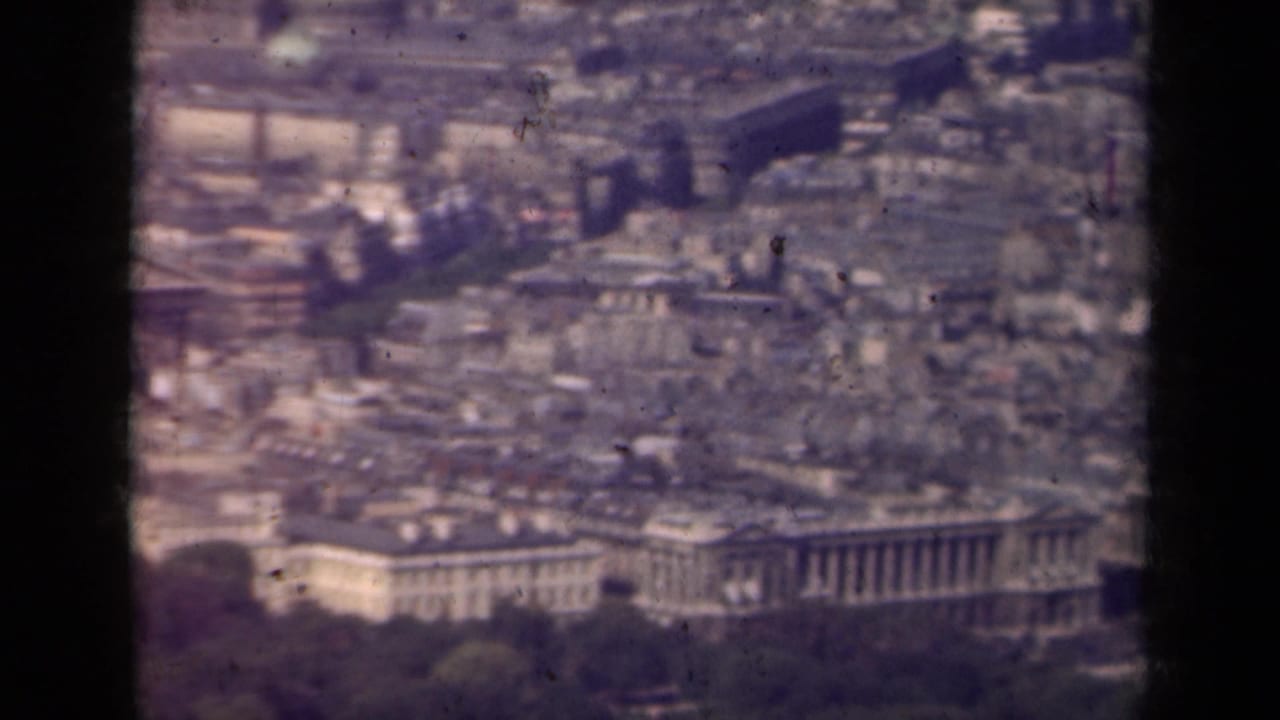 Soft aerial view over dense Paris rooftops and large classical buildings.